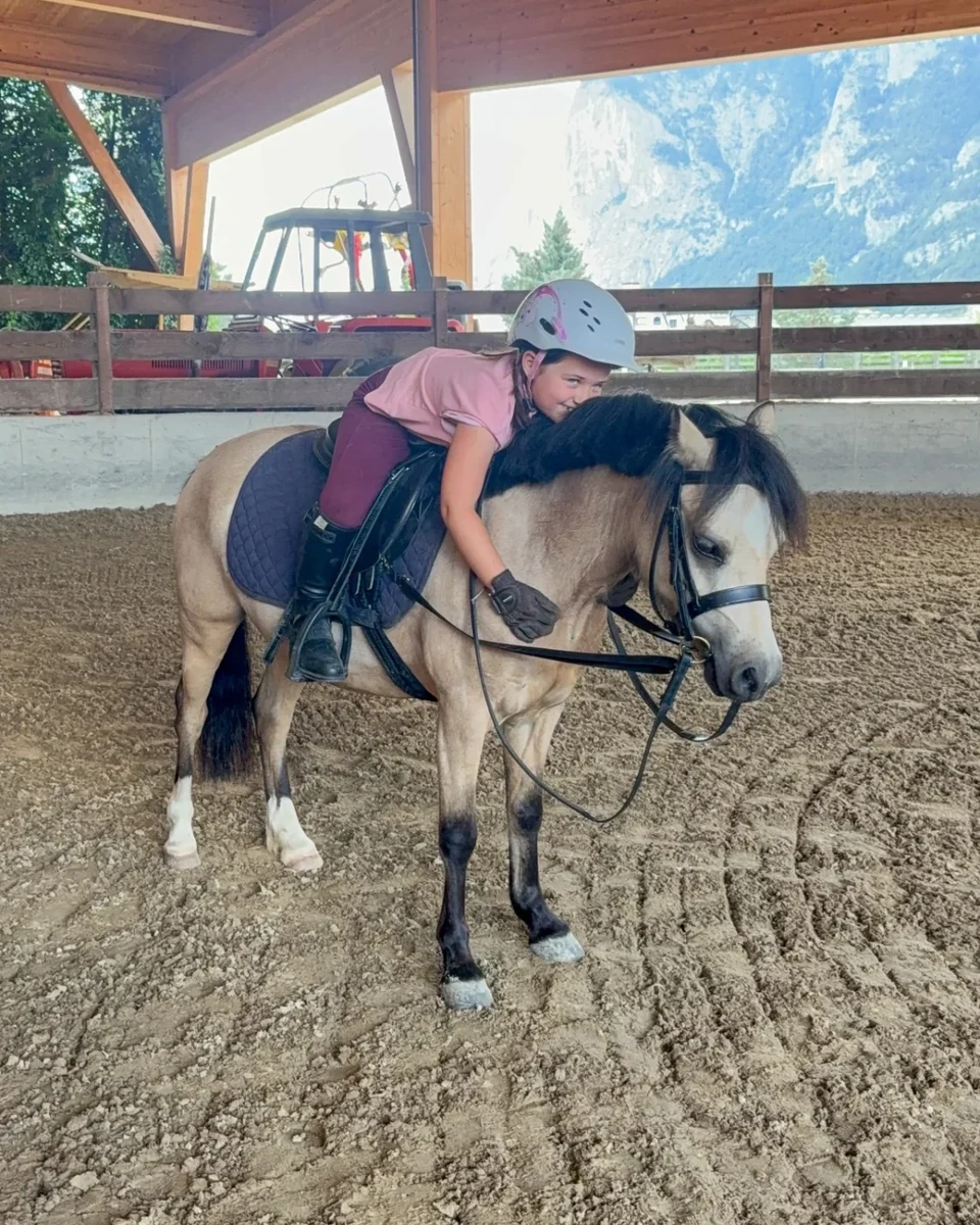 Ein Kind umarmt sein Pony in der Reithalle