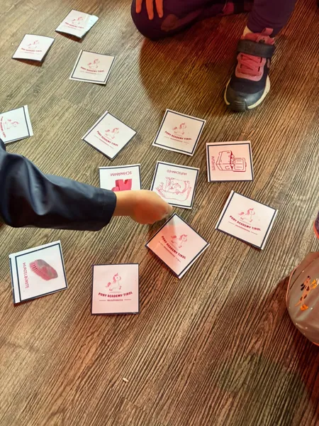 Kinder spielen mit bebilderten Karten auf einem Holzboden.